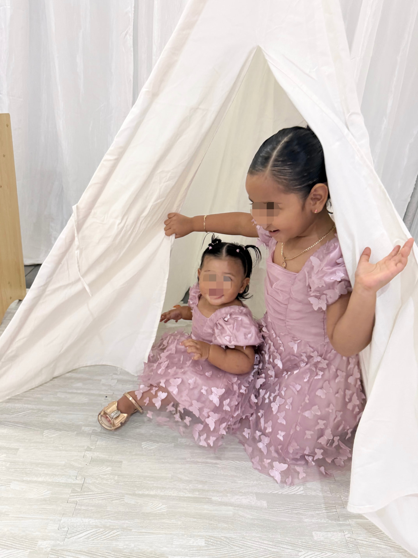 Two little girls smiling inside a white play tent