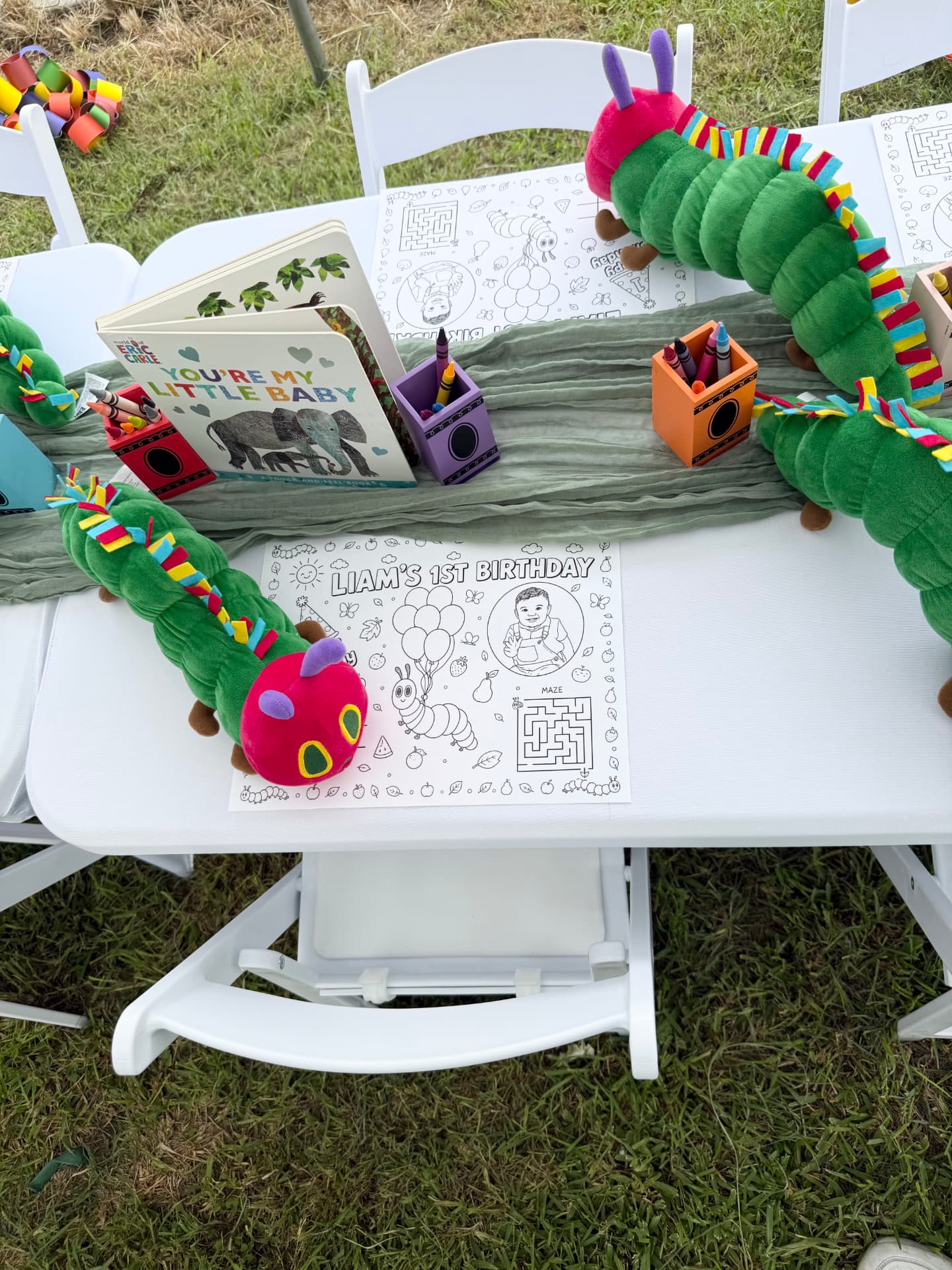 Caterpillar-themed birthday activity table with books and coloring pages